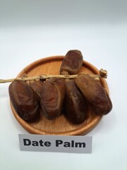 Date palm fruit on a small wooden plate. Date palm fruits, or simply dates, are the oval-shaped, sweet, edible fruit of the date palm tree (Phoenix dactylifera)