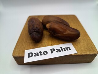 Date palm fruit on wooden serving board. Date palm fruits, or simply dates, are the oval-shaped,...