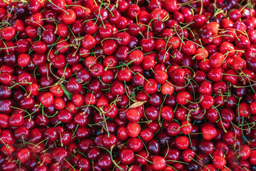 Ripe sweet cherries as background, top view. Fresh ripe cherries with stems, bright natural light. Natural background, texture. Concept of cherries, organic fruit, summer harvest, healthy eating