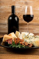 Cheese plate of color cheeses variety, yellow, white and blue gorgonzola platter with red wine glass