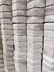 A close-up view of stacked gray concrete paving blocks with rough textures and visible layers