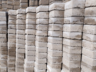 Rows of stacked gray concrete paving blocks with rough surfaces and layered textures
