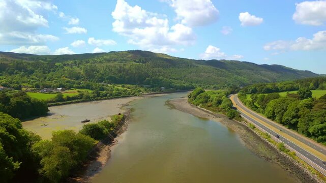 Wide, rising aerial video of the Newry River and Mourne Mountains in Warrenpoint, County Down, Northern Ireland, UK on a bright and sunny day. Filmed in 4K, 60FPS and with Rec709 color.