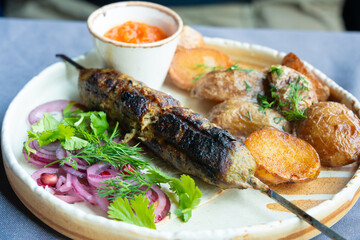 Georgian lula kebab plate. Bbq skewer, traditional barbecue dish with baked potatoes, sauce
