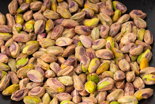 Fried salt pistachio nuts texture background. Baked pistachios grains pattern, pistache fruits