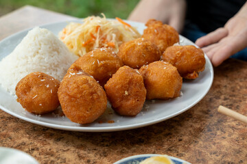 Fried chicken balls with rice and fresh cabbage salad closeup. Deep fried dough balls