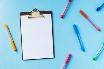 Clipboard and colorful pens on blue backgound