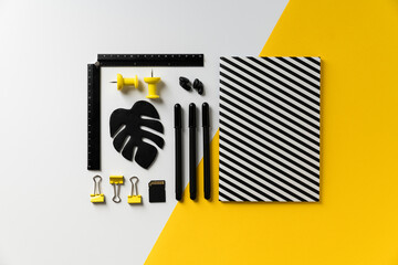 White, black and yellow back to school flat lay with notebook, pen, pushpins, ruler
