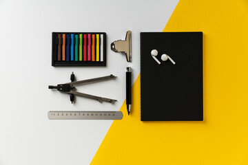 White, black and yellow back to school flat lay with colorful crayons, drawing tools