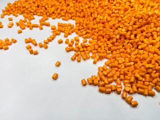 Orange polymer granules, orange masterbatch granules, cold cutting material type, isolated on white background for product catalog design of plastic manufacturing industry company profile
