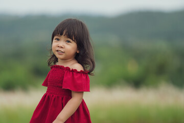 cheerful toddler girl in red dress playing in grass field