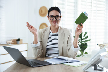 Travel agent with passport and ticket at wooden table in office