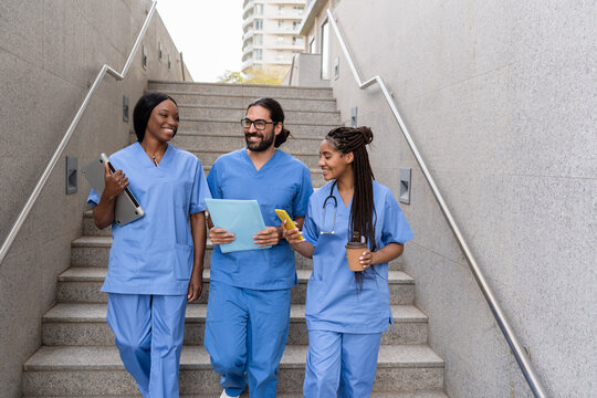 Cheerful Doctors and nurses walking down stairs at hospital discussing patient information
