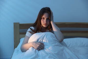 Frustrated young woman suffering from insomnia on bed indoors