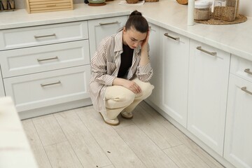 Emotional woman looking in disgust at cockroaches on floor indoors. Pest problem