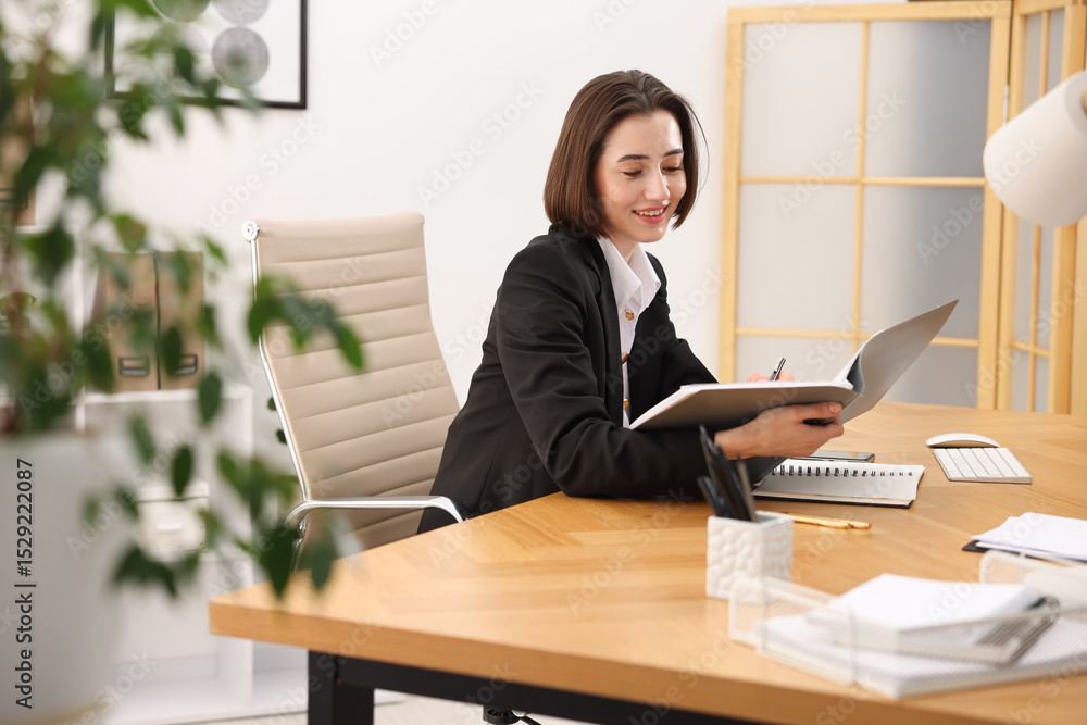 Poster smiling secretary with folder at table in office
