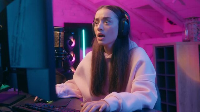 Frustrated sad woman gamer girl female streamer in headphones worry upset with fail loss bad result failure at computer online game playing in neon home room at night addiction gaming problem stream
