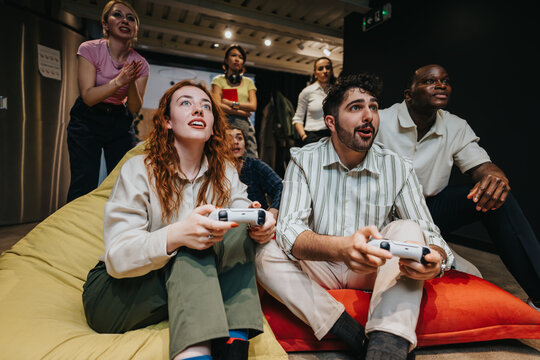 Diverse group of colleagues gathered together, energetically playing video games and enjoying their shared experience.