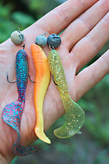A man's hand holds a set of silicone fishing lures. Fishing tackle, sport fishing.