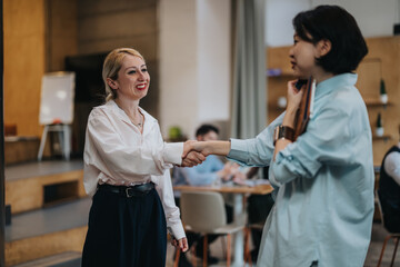 Two individuals are shaking hands in a cozy co working space, signifying collaboration or partnership.