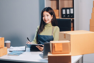 Startup SME small business entrepreneur of freelance Asian woman wearing apron using laptop and box...