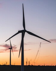 Minimalist Wind Turbines Silhouetted at Dusk. Modern Wind Farm Against a Dramatic Sunset Sky with Soft Muted Colors. Concept for Renewable Energy & Sustainability