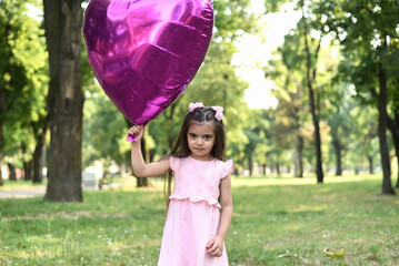 Little girl of 4 years with a big pink heart balloon
