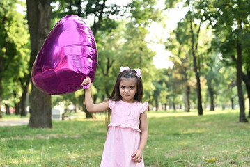 Little girl of 4 years with a big pink heart balloon