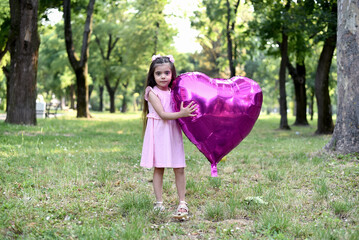 Little girl of 4 years with a big pink heart balloon