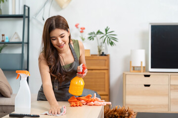 Cleaning housework with cheerful woman disinfecting table at home