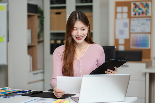 Female coder or developer working  using a Tablet and computer display in problem solving at workplace.