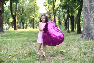 Little girl of 4 years with a big pink heart balloon