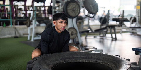 Tire Workout. A man lifting a heavy tire in a gym for strength training.