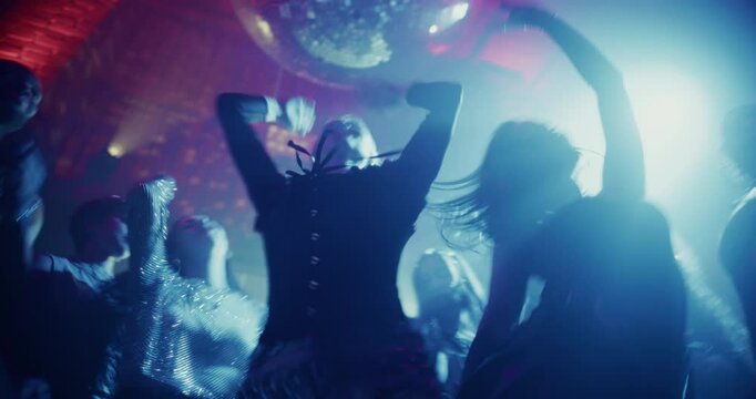 Partygoers Dancing Freely in a Dark Club Filled with Colorful Strobe Lights. Young Adults Enjoying a Night Out at an EDM Party. Stylish Men and Women Enjoying a Disco at a Nightclub