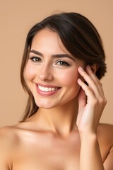 A woman smiles brightly with her hand near her face in a close up studio portrait shot.