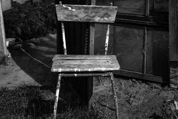 A lone chair stands as a silent sentinel, weathered by time and etched in monochrome. A forgotten...