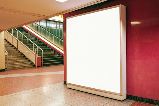 White blank billboard mockup inside subway station with stairs and modern interior. Ideal for advertising, poster, or banner display in urban public transport settings.

