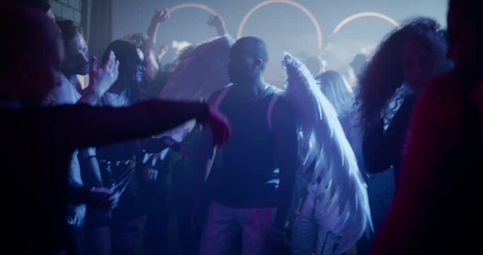 Graceful Black Man Dances in a Rave Scene Wearing Large White Angel Wings Among a Lively Crowd of Men and Women. Atmosphere Blends Divine Imagery with Electrifying Nightlife Culture