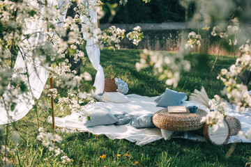 Cozy picnic setup in a flower-filled garden by a serene waterbody