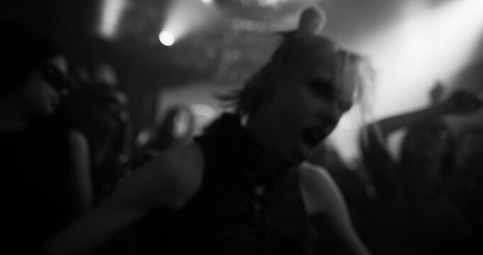 Energetic Woman with Blonde Hair Revels on a Rave Dancefloor, Surrounded by a Lively Crowd Under Pulsating Lights, Capturing the Essence of Nightlife Euphoria. Black and White Slow Motion Footage
