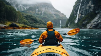 A lone kayaker navigates a tranquil waterway surrounded by majestic mountains and cascading waterfalls, embodying adventure and connection with nature's beauty.