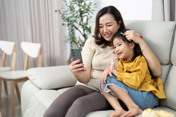 Obraz premium Mother and Daughter Smiling Together. Capturing joyful video moments on a smartphone.