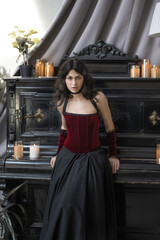 Portrait of a girl in a red vintage velvet corset at the piano