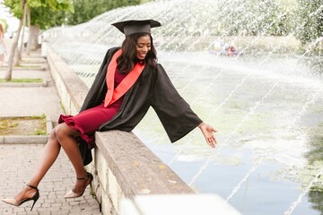 Young graduate touching water of a fountain in university campus