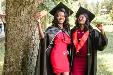 Two happy students taking selfie after graduation ceremony
