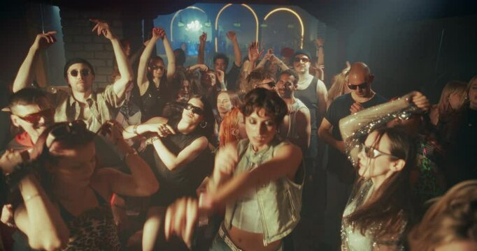 Diverse Party Crowd Enjoying Time in an Underground Nightclub, Dancing Energetically Under Dynamic Lights and Pulsating Music. Young Men and Women Having an Emotional Night Out. Slow Motion Footage