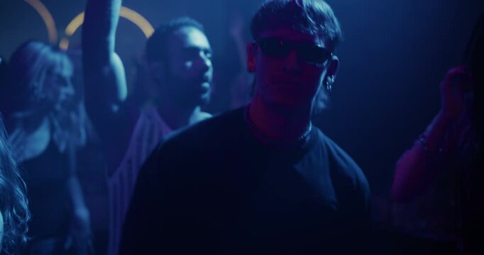 Partygoers Dancing in a Dark Club Filled with Colorful Strobe Lights. Young Adults Enjoying a Night Out at an EDM Party. Stylish Men and Women Enjoying a Disco at a Nightclub. Slow Motion Footage