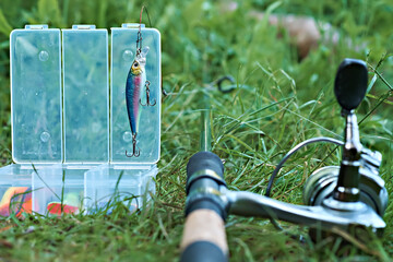Wobbler with a box for accessories on the background of a spinning reel. Fishing tackle. Selective focus.