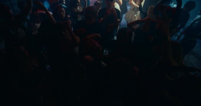 Partygoers Dancing in a Club with Colorful Strobe Lights. Young Adults Enjoying a Night Out at an EDM Party. Stylish Men and Women Enjoying a Disco at a Nightclub. Slow Motion High Angle Footage