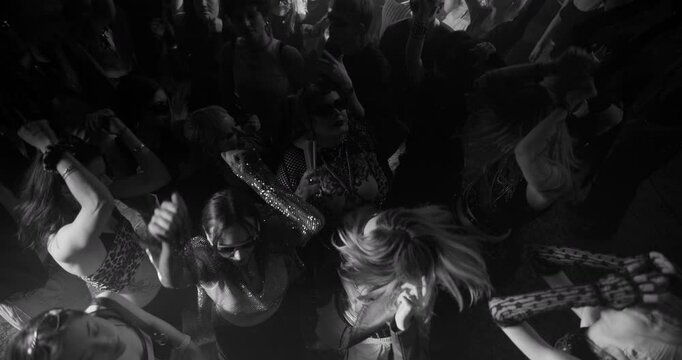 Party Crowd Enjoying Time in a Nightclub, Dancing Energetically Under Lights and Pulsating Music. Young Men and Women Having an Emotional Night Out. Slow Motion Top Down Black and White Footage
